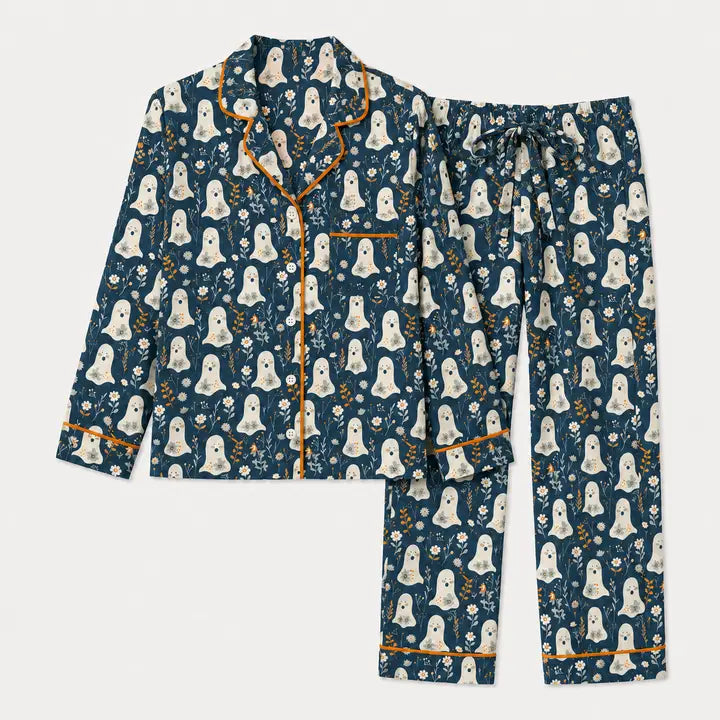 A two-piece pajama set featuring a long-sleeve button-front top and matching pants in a dark teal blue color, decorated with a repeating white ghost pattern and trimmed with orange piping.