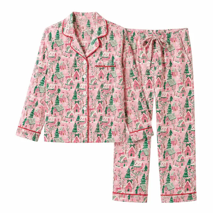 A two-piece pajama set featuring a long-sleeve button-front top and matching pants, both in a pink gingerbread print with green trees and red trim, shown on a plain white background.