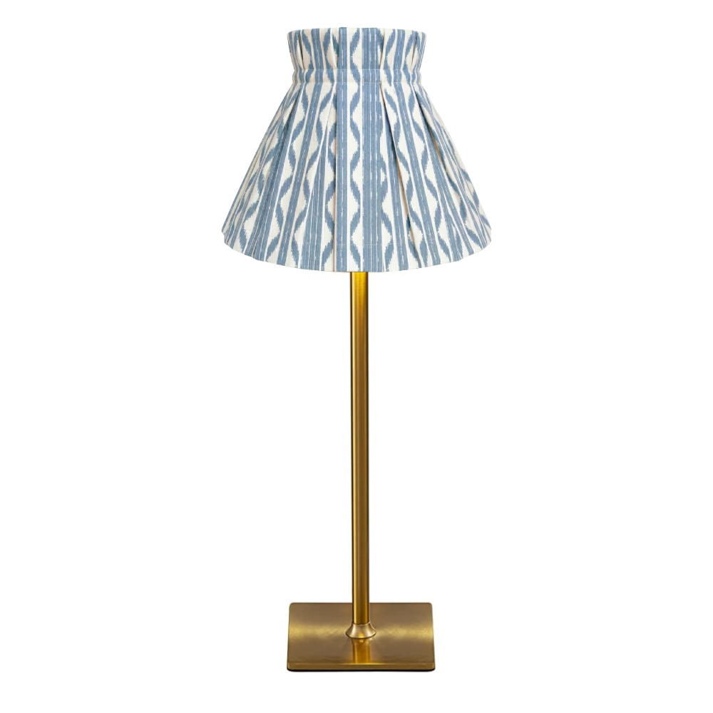 Table lamp with a blue and white patterned cover shade on a gold base against a white background