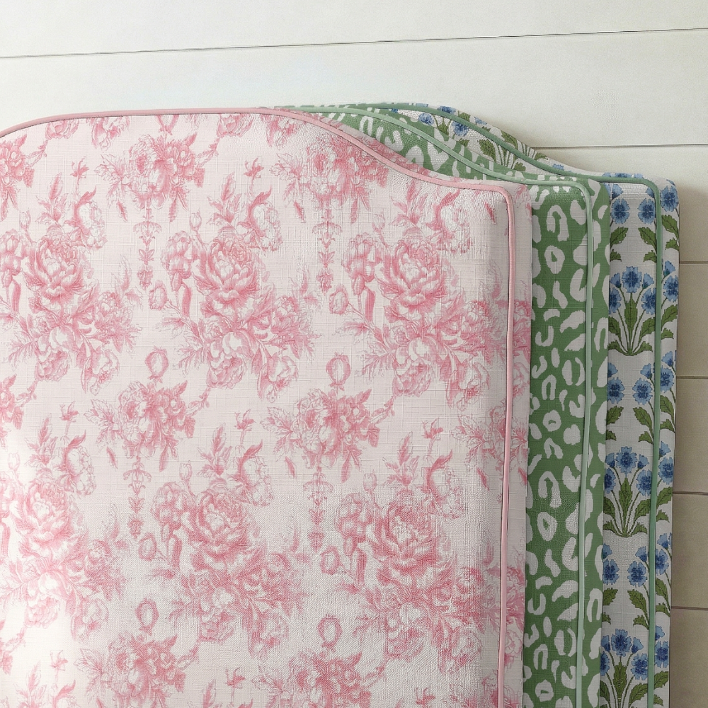 Two fabric swatches with floral and leopard print patterns on a wooden surface.