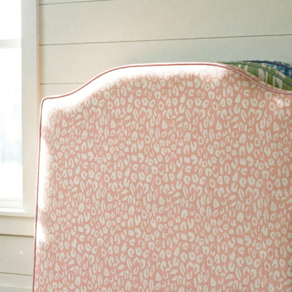 Pink fabric with a subtle pattern draped over a chair in a room with light-colored walls.