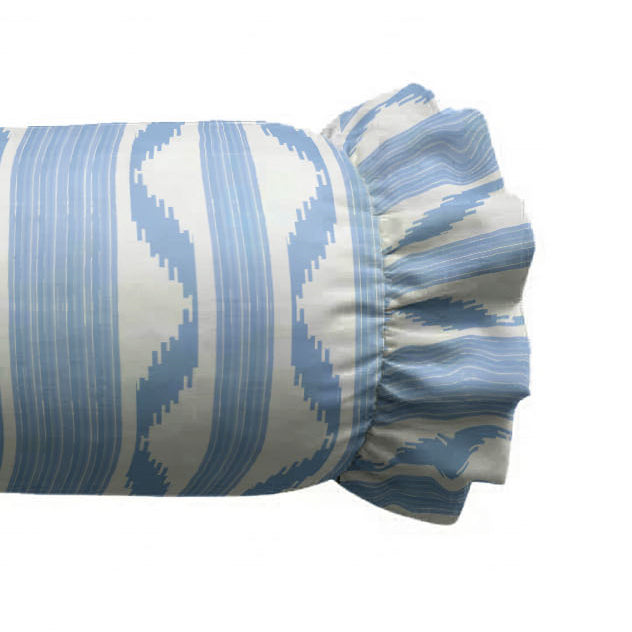 Zoom of decorative cylindrical pillow with a blue and white pattern on a white background