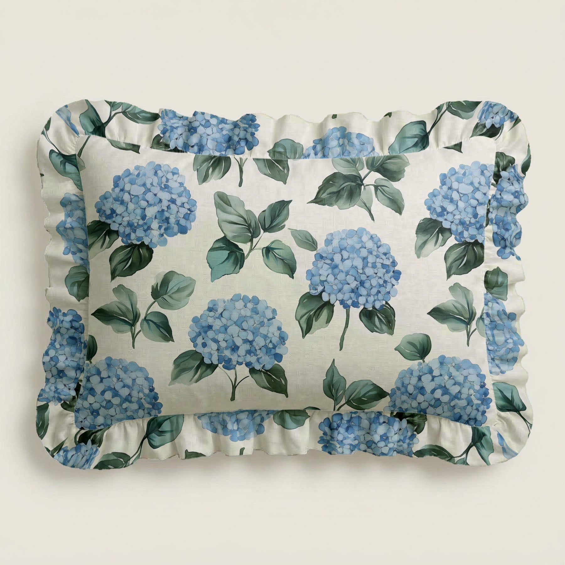 Floral pillow with blue hydrangeas and green leaves on a white background
