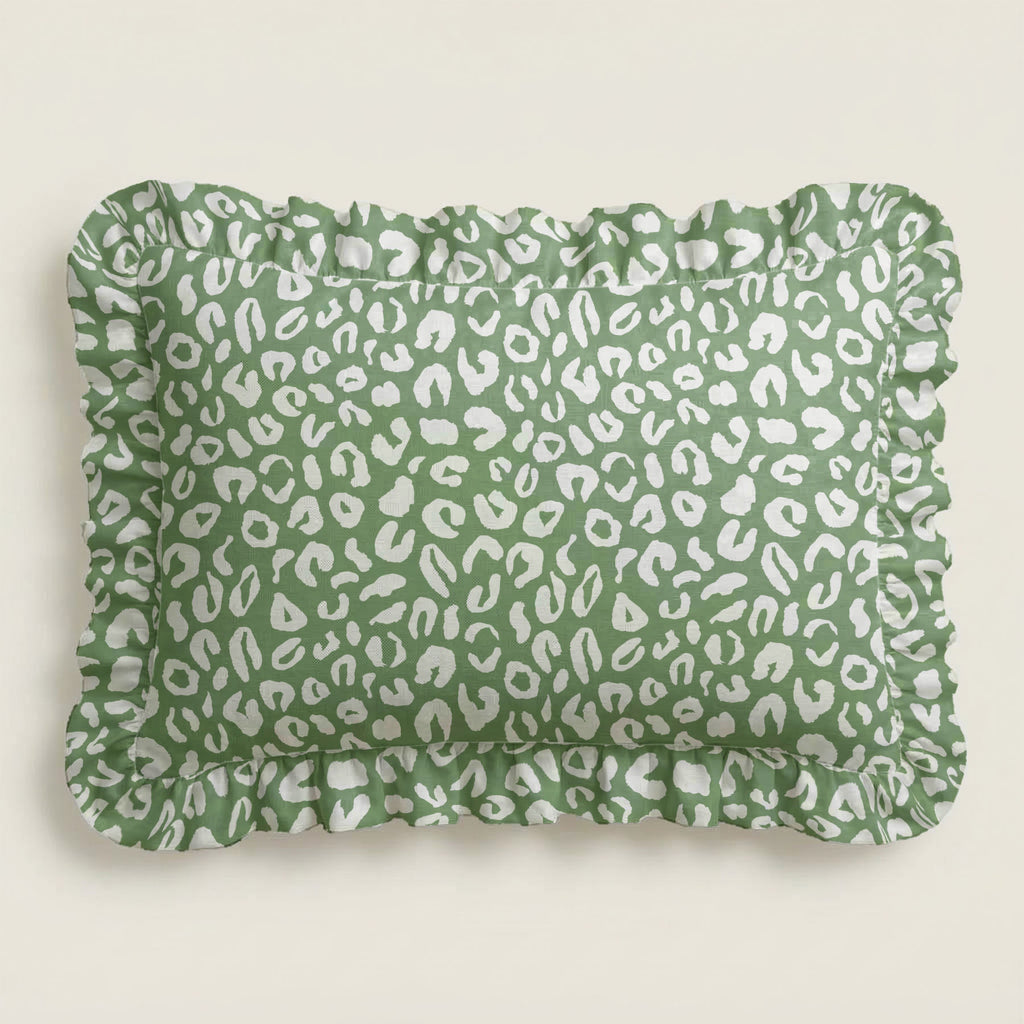 Green pillow with white leopard print pattern on a light beige background