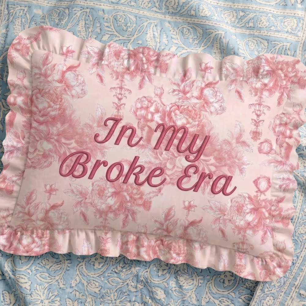 Floral pillow with 'In my Broke Era' text on a patterned fabric background
