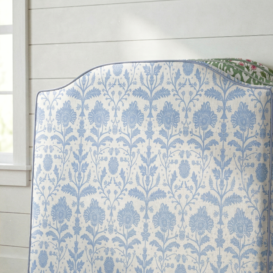Blue floral patterned quilt on a bed with a white wooden headboard.