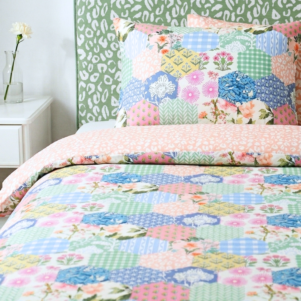 Colorful floral quilt and pillow on a bed with a green headboard.