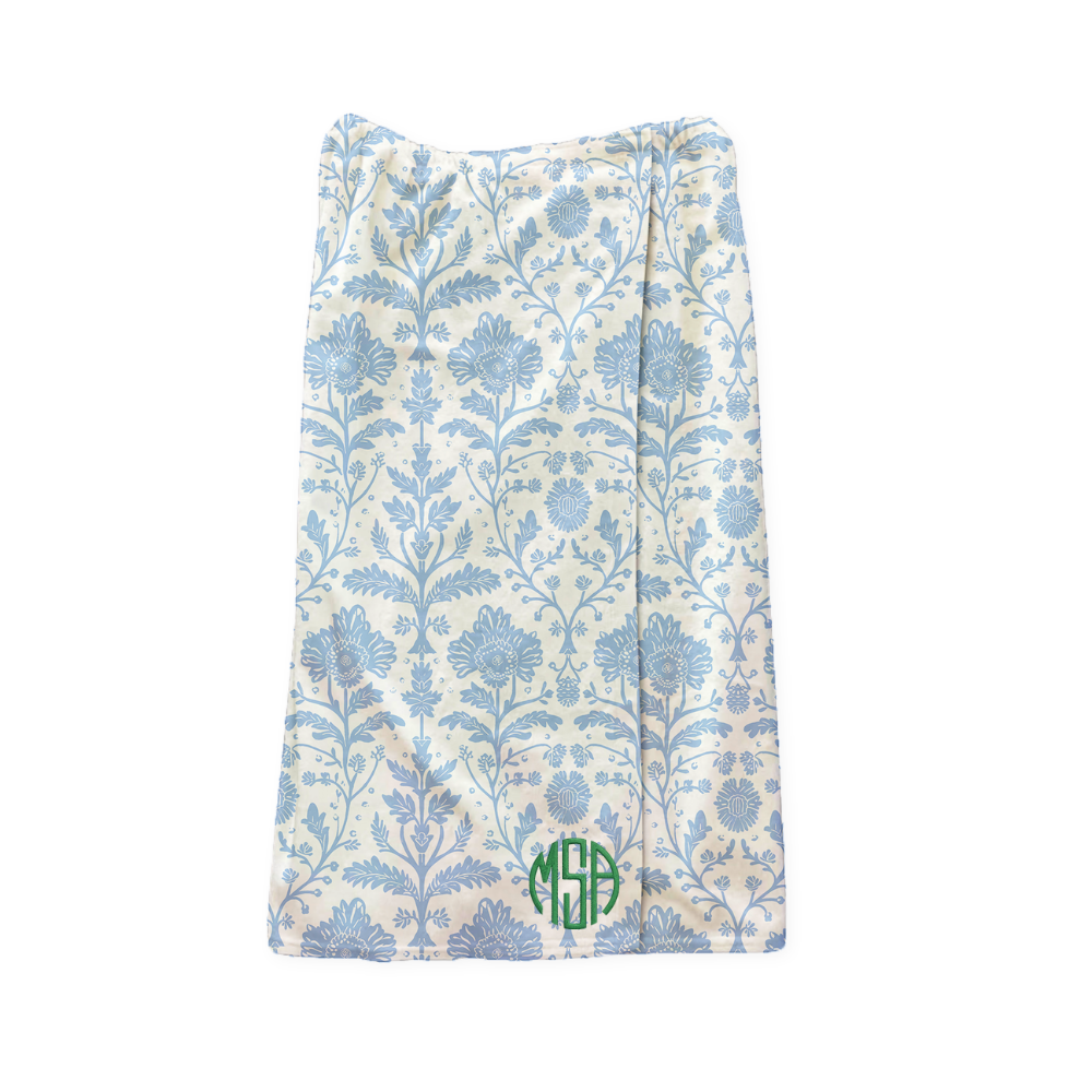 Floral patterned wrap towel with a green monogram on a white background
