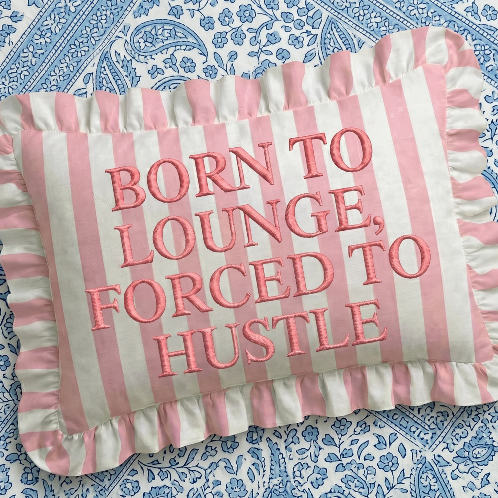 Striped pillow with pink text on a blue patterned background